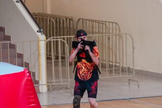 Боец LASERWAR в яркой футболке целится из автомата.